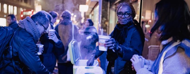 A community event on a high street where people are serving hot soup 