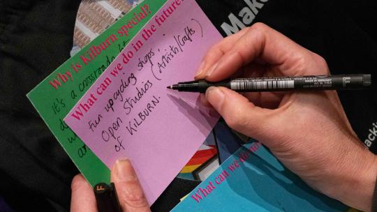 Close up of someone writing on their thoughts at a public engagement event