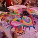 A group of participants colouring in a large illustration on a table during the Rewire summit.