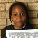 Young girl poses for photo with a Festival of Ideas poster she made